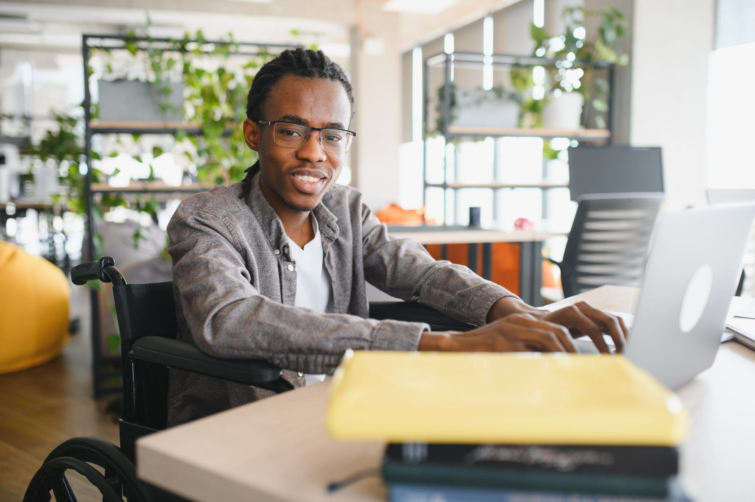 Young man in wheelchair using a laptop at a desk